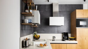 A modern kitchen with a built-in oven, a coffee maker, and a fruit bowl on the counter. - Aris Apartments & Sky Pool - Tonelli Hotels - Adults Only (Riva del Garda)