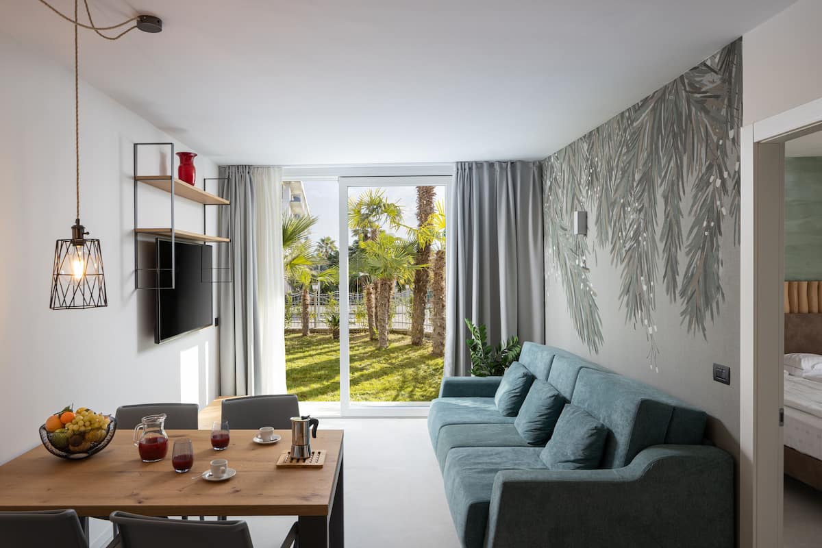 Een moderne woonkamer met een bank, een eettafel en een aan de muur bevestigde televisie.