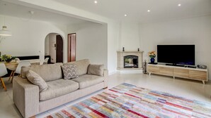 A living room with a sofa, TV, fireplace, and a colorful rug. - Vila Casa do Cerro with Pool, Garden & Wi-Fi (Boliqueime)