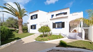 A two-story building with a white facade, blue shutters, and a paved entrance. - Vila Casa do Cerro with Pool, Garden & Wi-Fi (Boliqueime)