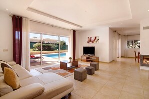 Una sala de estar moderna con sofá, pufs, televisión y chimenea.