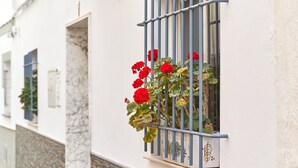 Un bâtiment aux murs blancs et doté d’une fenêtre ornée d’une grille métallique.