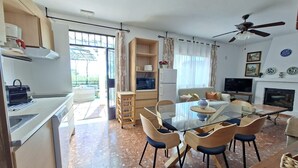 A modern kitchen with a dining area, a TV, and a fireplace. - Holiday Home 'Sailor House Slow Life In Nature' with Mountain View, Wi-Fi and Air Conditioning (Málaga)