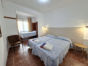 Ein Hotelzimmer mit einem Bett, einem Sessel, einem kleinen Tisch und einem fenster mit Vorhängen.