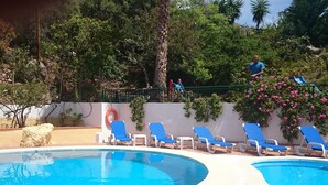 A pool area with two pools, blue lounge chairs, and a person on a balcony. - Country House 'Santa Matilde Málaga' with Sea Views, Wi-Fi and Air Conditioning (Málaga)