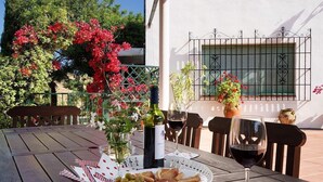 An outdoor dining area with a table set for two, featuring a bottle of wine, glasses, olives, and bread. - Country House 'Santa Matilde Málaga' with Sea Views, Wi-Fi and Air Conditioning (Málaga)