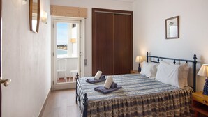 Un dormitorio con cama, lámparas de noche, una puerta y vistas a través de la puerta.