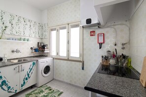 A kitchen with a washing machine, a sink, and a window.