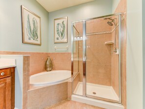 Een badkamer met een douche in een glazen cabine, een vrijstaand bad en een wastafel met spiegel.