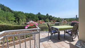 Une terrasse avec une table et des chaises, un mur en pierre et des plantes en pot.