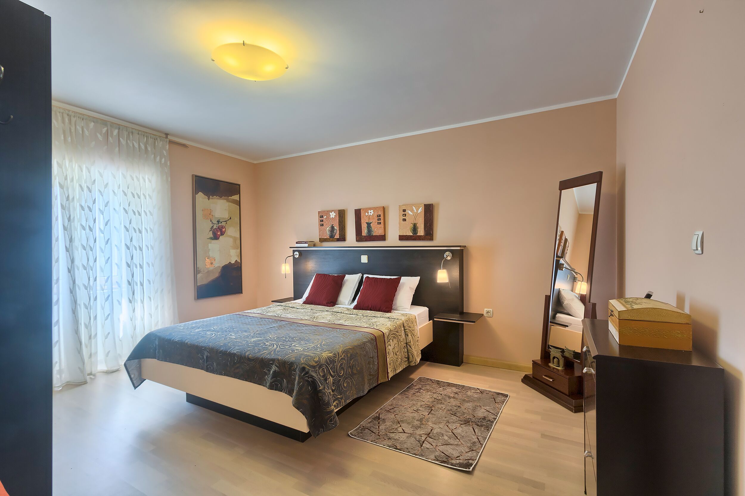 Une chambre à coucher avec un lit, des tables de chevet, un miroir et des œuvres d’art accrochées au mur.