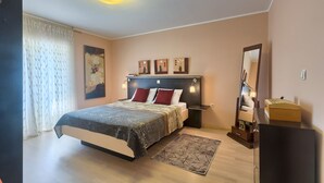 Une chambre à coucher avec un lit, des tables de chevet, un miroir et des œuvres d’art accrochées au mur.