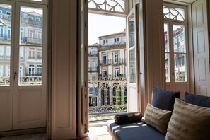 A room with a balcony, a sofa with cushions, and a view of neighboring buildings. - BEAUTY PORTO - Charming apartment with balcony located in downtown Porto (Porto)
