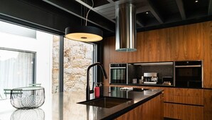 A modern kitchen with a large island, stainless steel appliances, and a stone wall.