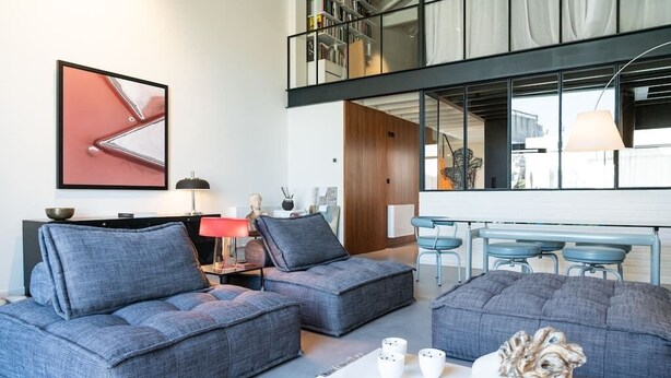 A modern living room with grey sofas, a coffee table, and a bookshelf.