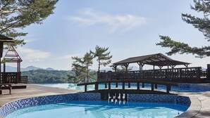 A swimming pool with a wooden deck, a gazebo, and a view of mountains.