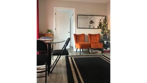Un salon avec un ventilateur de plafond, une table à manger avec des chaises et un tapis noir et blanc.