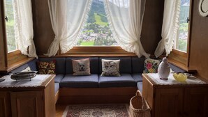 A cozy room with a window seat, a view of a village, and a rustic wooden interior.