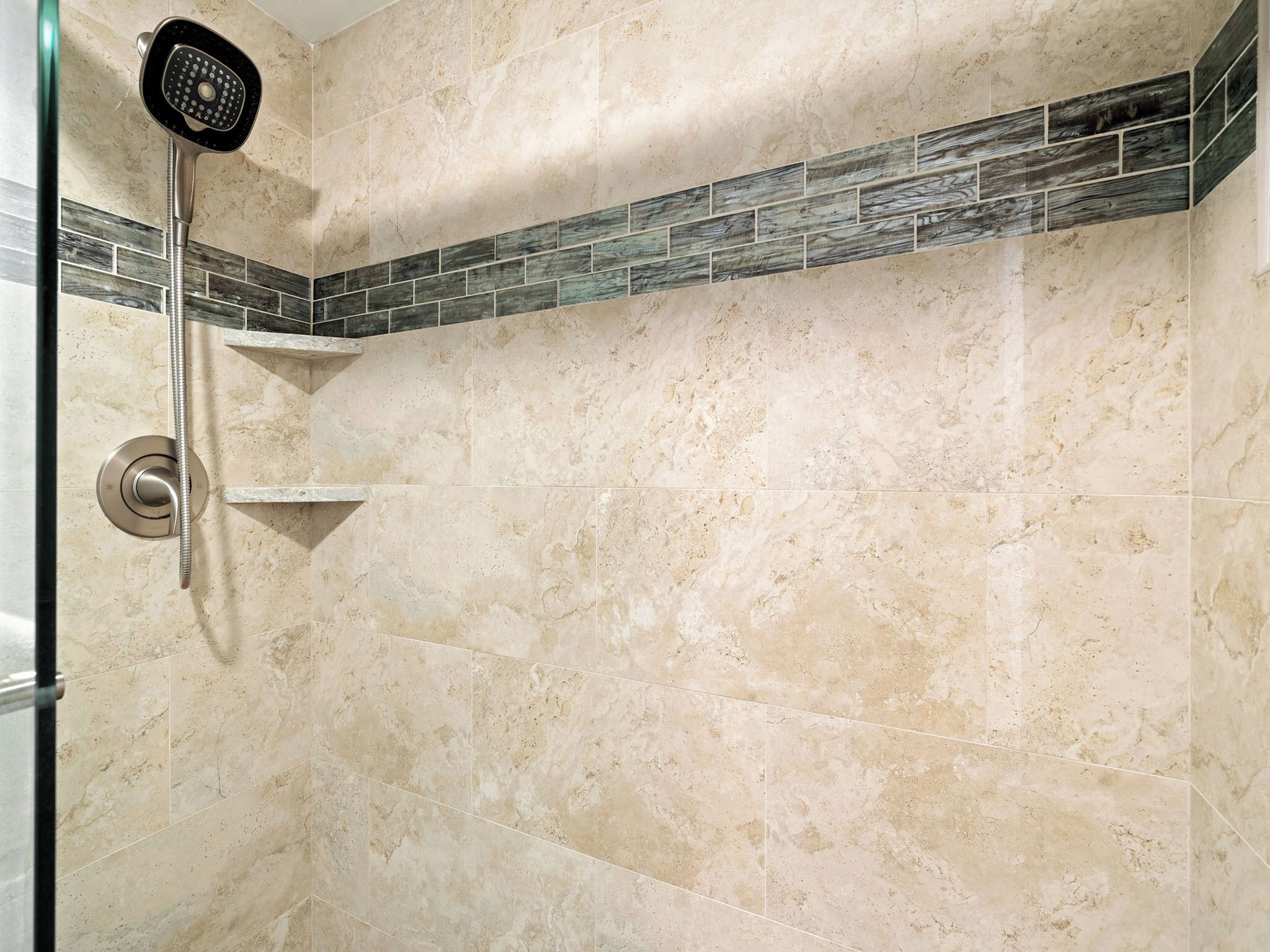 A shower with a handheld showerhead and a wall-mounted control.
