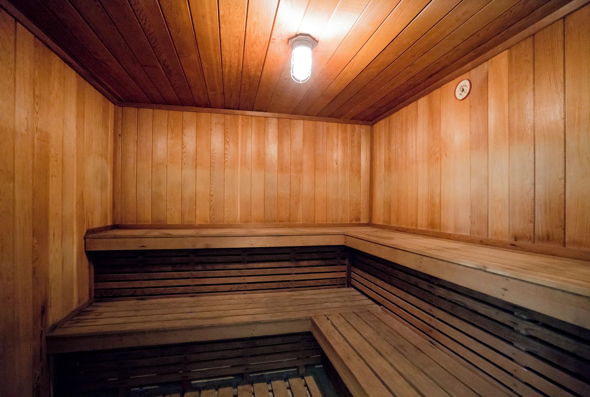 Eine Holzsauna mit Bänken und leicht abschüssigem Boden.