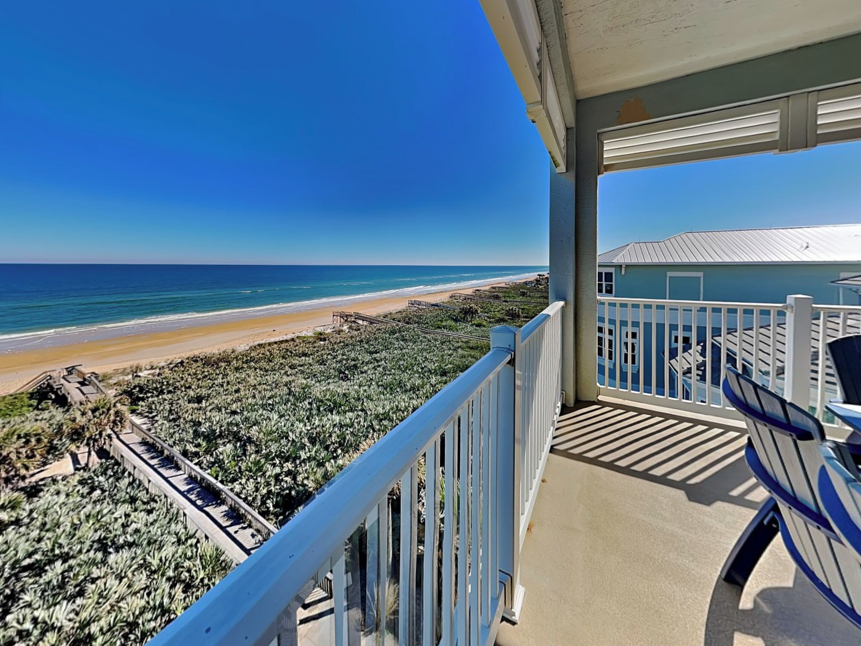 A balcony with a view of the beach and ocean.
