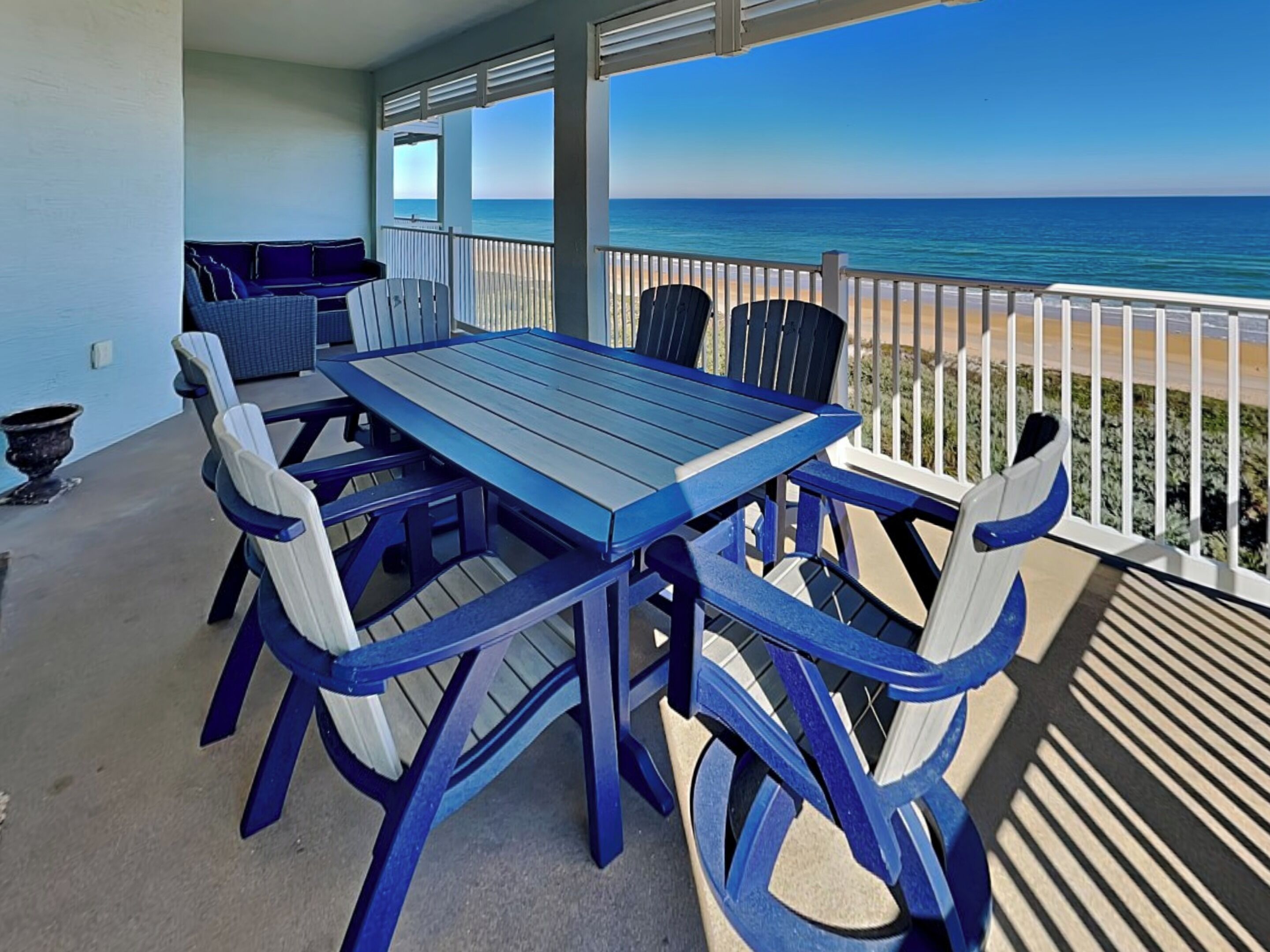 Une terrasse couverte, dotée d’une table et de chaises, qui offre une vue sur la plage.