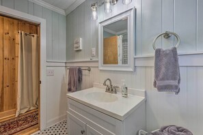 A bathroom with a wooden door, a white sink with a mirror above it, and a towel rack with a towel. - Near Hiking: Roaring Gap Retreat w/ Fire Pit! (Roaring Gap)