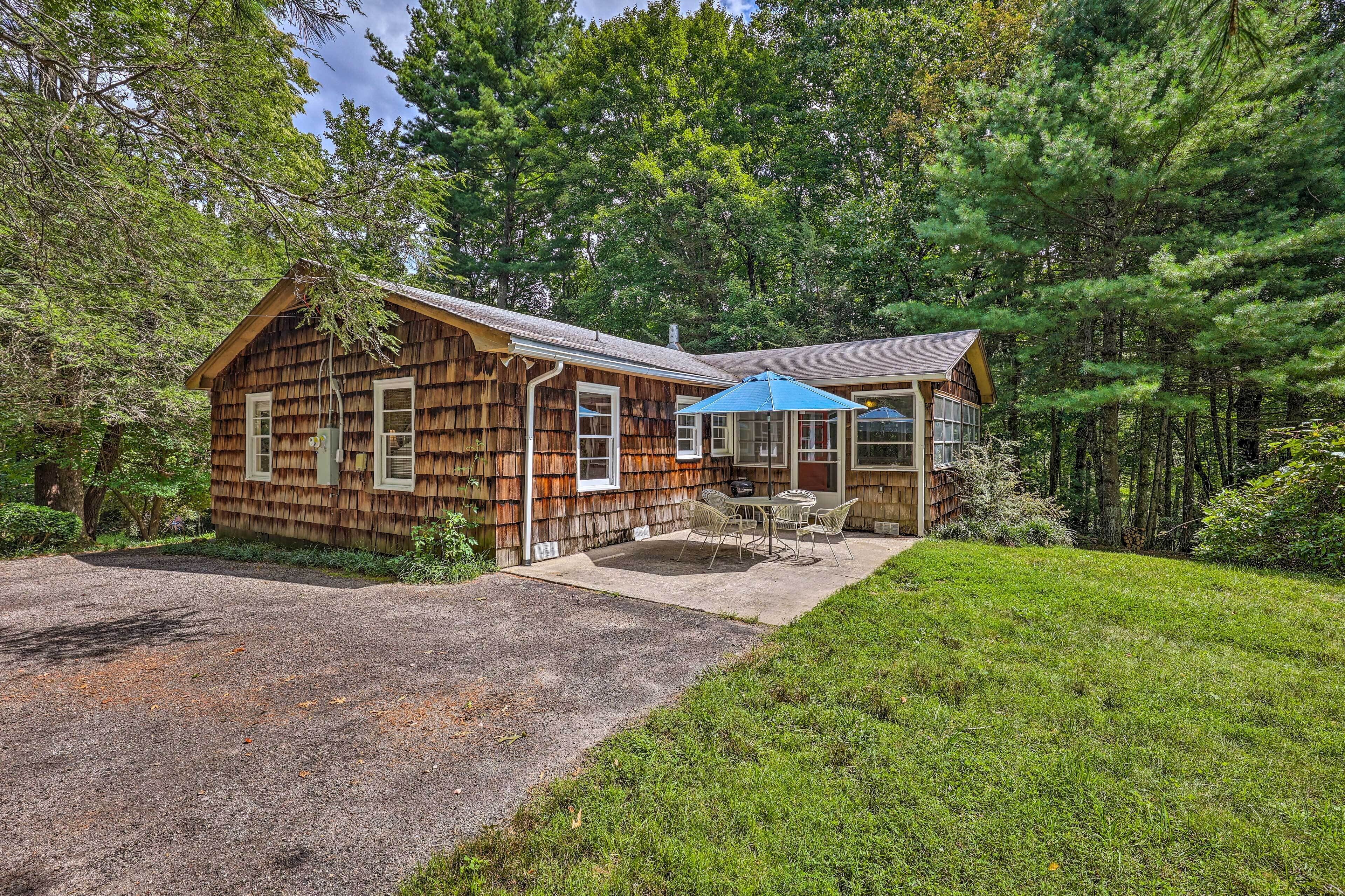 A rustic cabin with a covered patio and a gravel driveway.