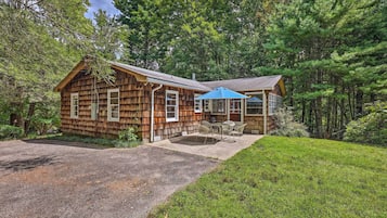 A rustic cabin with a covered patio and a gravel driveway.
