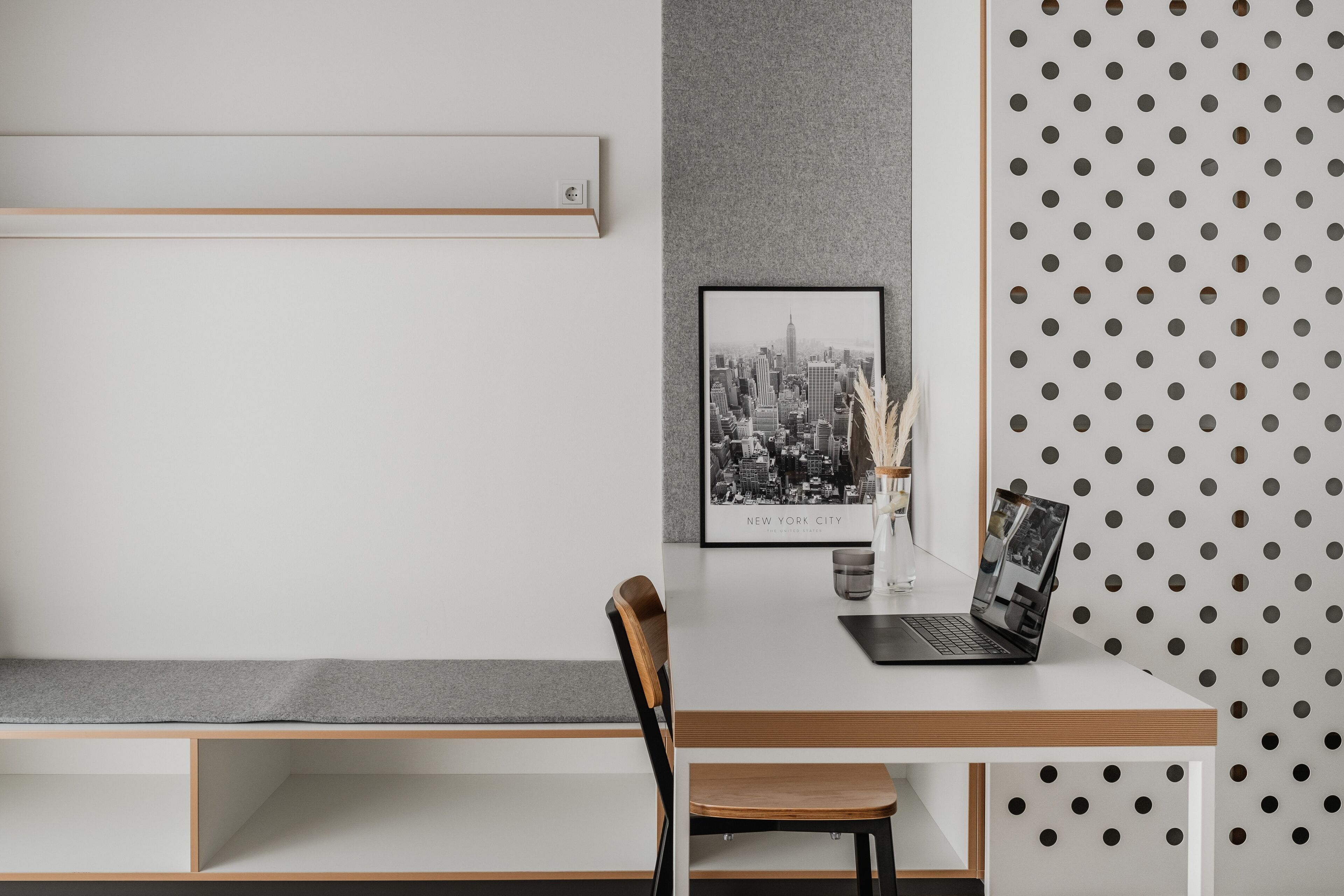 A modern workspace with a desk, chair, and a framed cityscape picture.