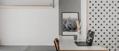 Un espacio de trabajo moderno con escritorio, silla e imagen enmarcada de un paisaje urbano.