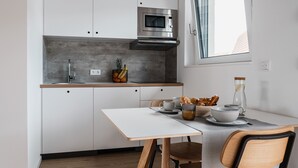 A modern kitchen with white cabinets, a stainless steel microwave, and a window above the sink. - CLOUD No7 STUDIOS (Tuebingen)