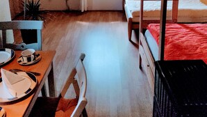 Habitación tipo dormitorio con literas, un escritorio con silla, una ventana con vistas a zonas verdes y una planta en maceta.