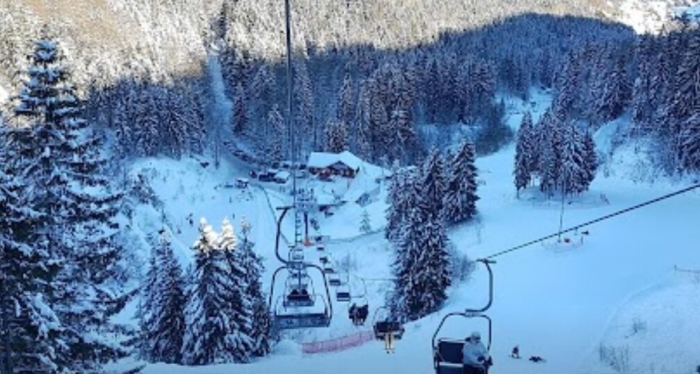A ski lift with cabins and a chairlift in a snowy forested area.