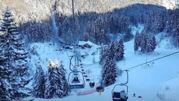 A ski lift with cabins and a chairlift in a snowy forested area.