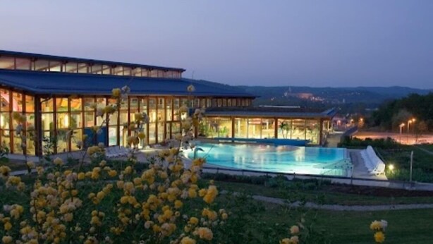 Un hotel moderno con piscina, amplias ventanas de vidrio y vistas del paisaje circundante.