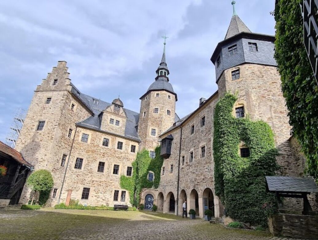 A historic stone building with multiple towers and arched walkways.