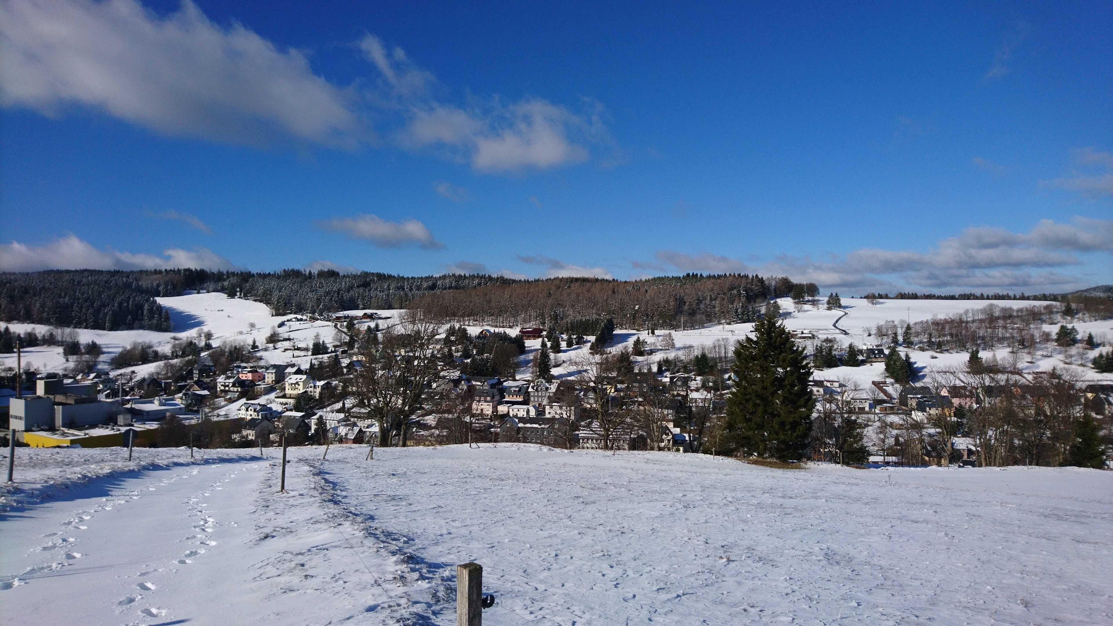 Een besneeuwd landschap met een stad in de vallei, gebouwen en een heldere lucht.
