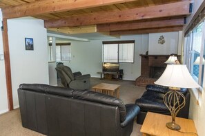A living room with a fireplace, leather sofas, and a wooden ceiling. - Bristlecone Lodge by Destination Big Bear : Beautiful Treed Setting Next to Snow Summit! Fenced Yard! (Big Bear Lake)