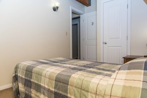 A bedroom with a bed, a door, and a wall-mounted light fixture.