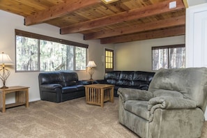 A living room with a high ceiling, two leather sofas, a wooden coffee table, and two lamps.