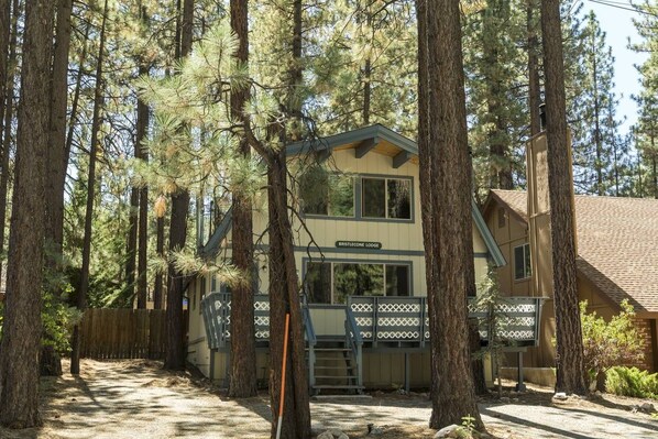 A lodge with a two-story structure, surrounded by tall pine trees. - Bristlecone Lodge by Destination Big Bear : Beautiful Treed Setting Next to Snow Summit! Fenced Yard! (Big Bear Lake)