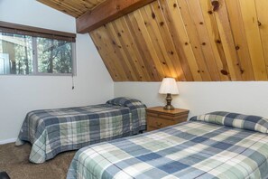 A bedroom with two beds, a nightstand, a lamp, and a window. - Bristlecone Lodge by Destination Big Bear : Beautiful Treed Setting Next to Snow Summit! Fenced Yard! (Big Bear Lake)
