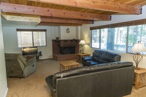 A living room with a fireplace, leather sofa, and a television.