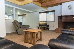 A living room with a fireplace, a leather sofa, a wooden coffee table, and a recliner.