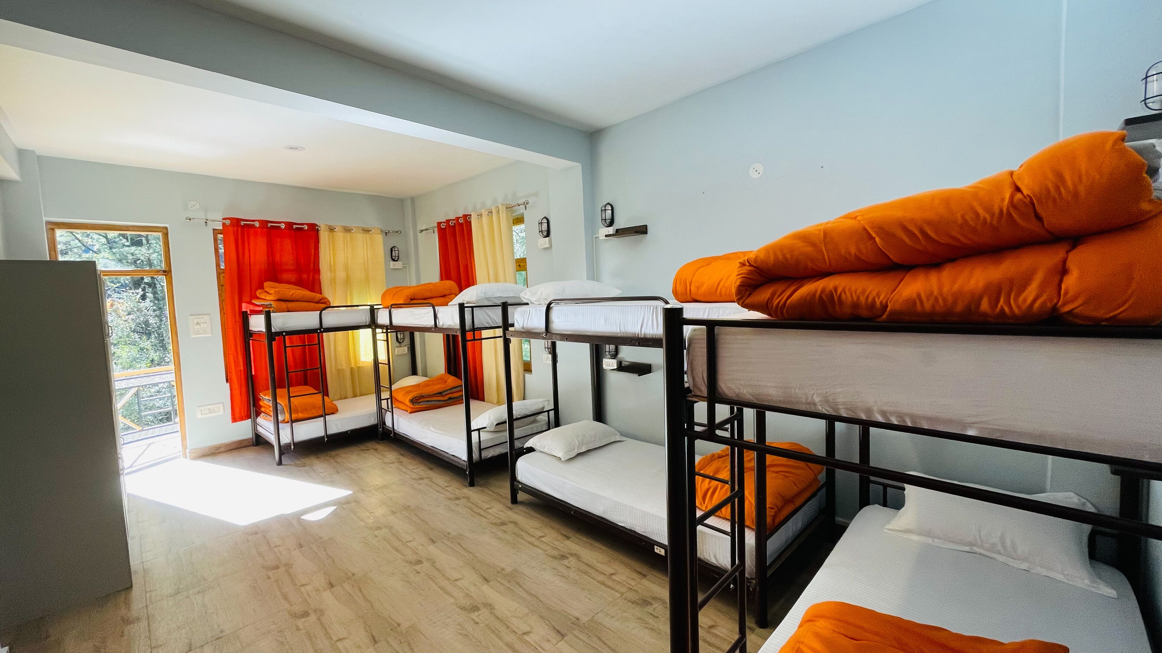 Un dormitorio con literas, una ventana con cortinas y una puerta que da al exterior.