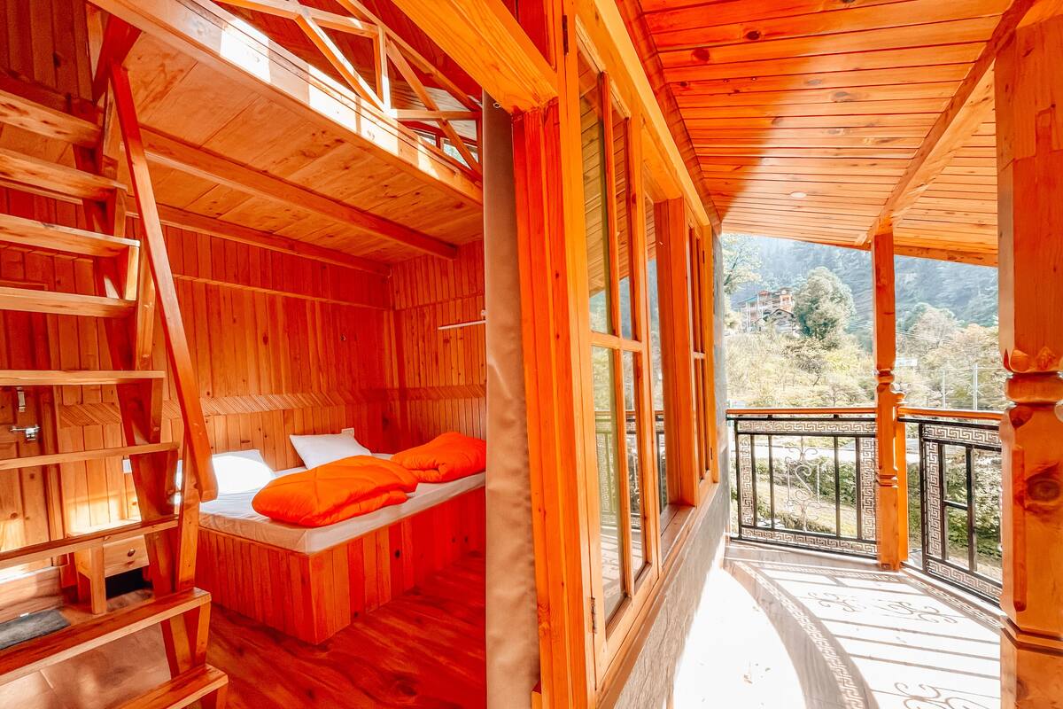 A wooden cabin with a loft bed, a small table, and a ladder.
