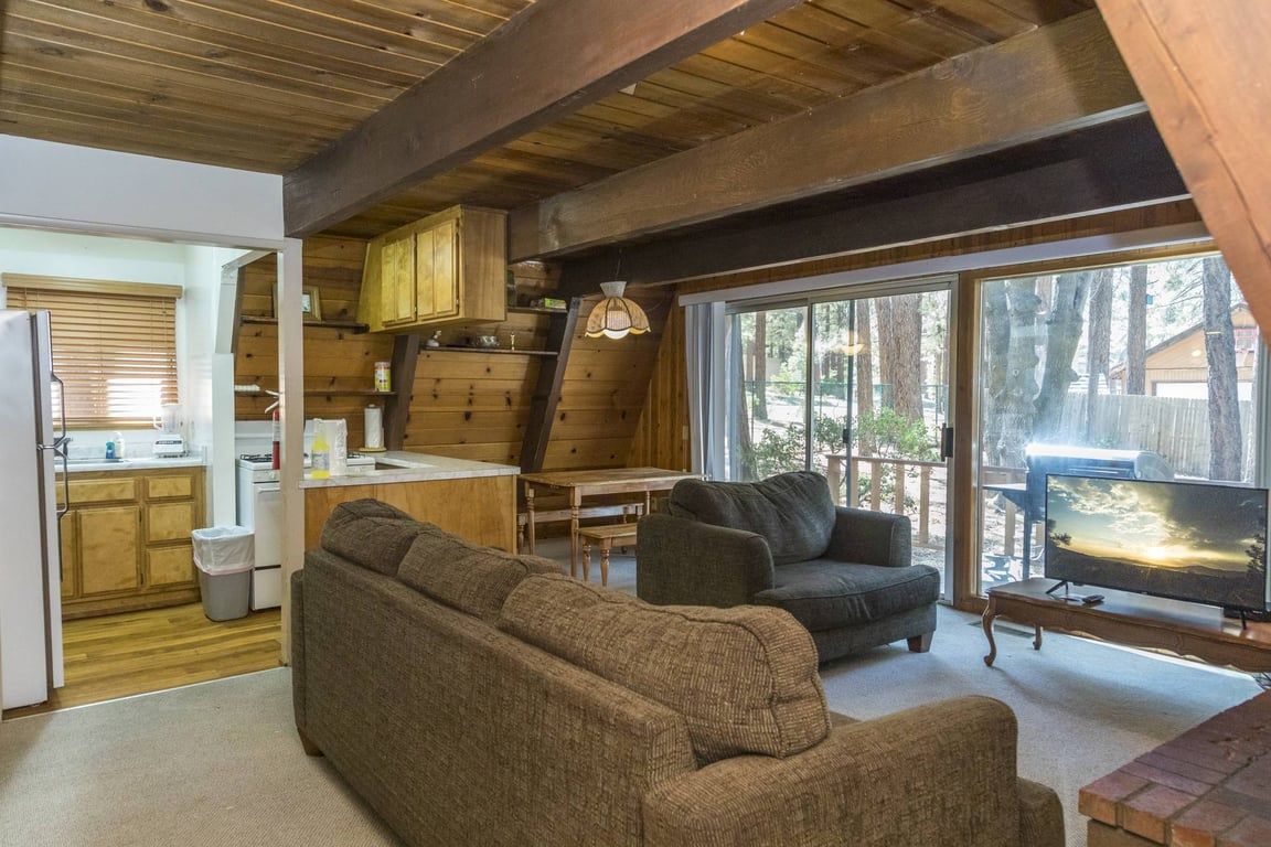 A cozy living room with a sofa, armchair, and a television.