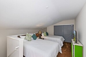 Ein Schlafzimmer mit zwei Betten, einem Fernseher und einem Kleiderschrank.