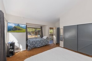 A bedroom with a large bed, a TV, and a view of a mountainous landscape.